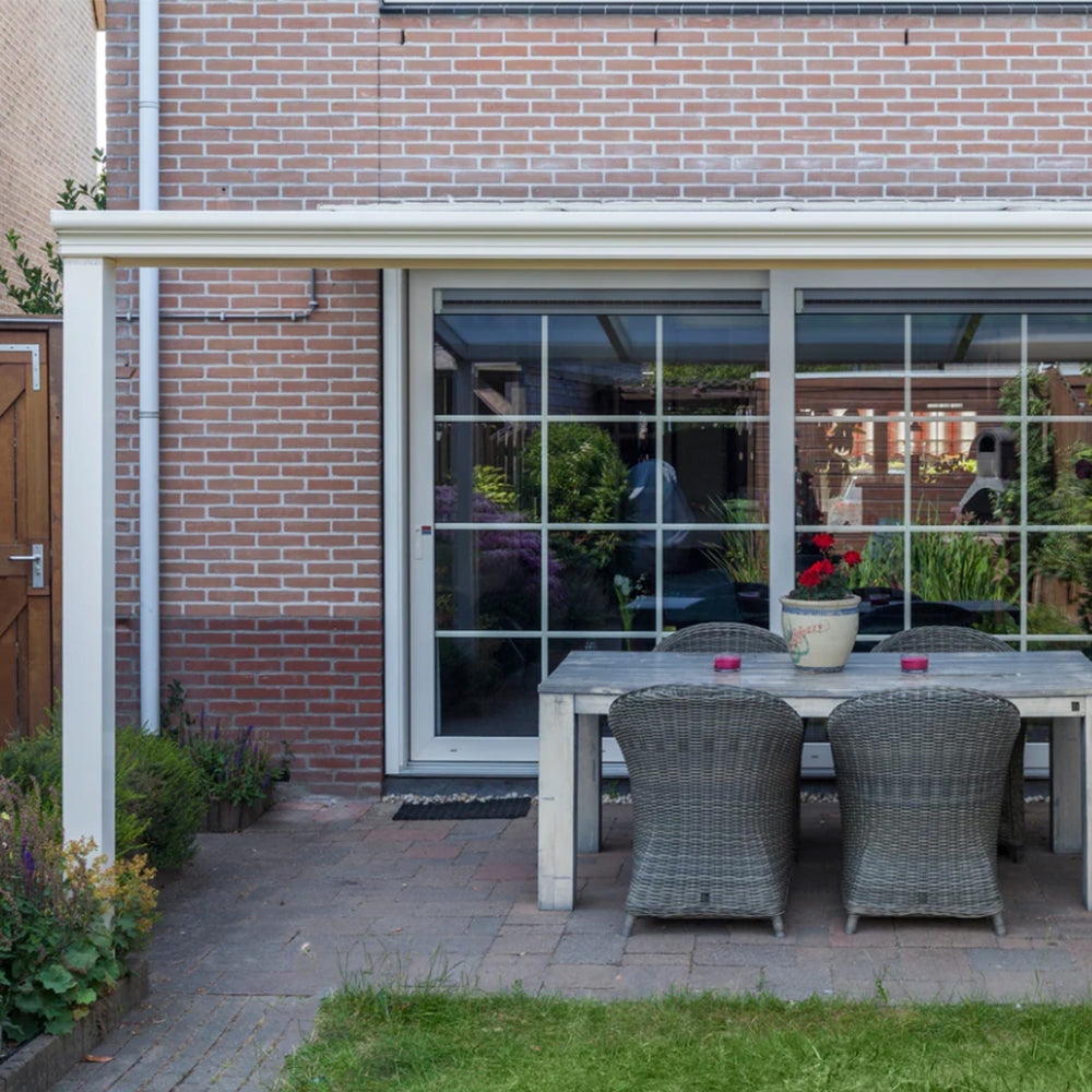 Outdoor dining area with table and chairs in front of a glass door.