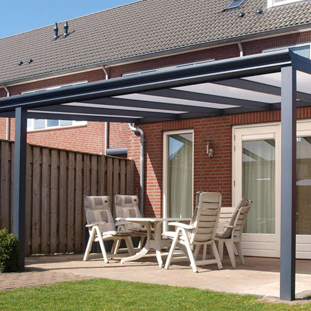 Outdoor patio with aluminium pergola, table, and chairs in front of a brick house.