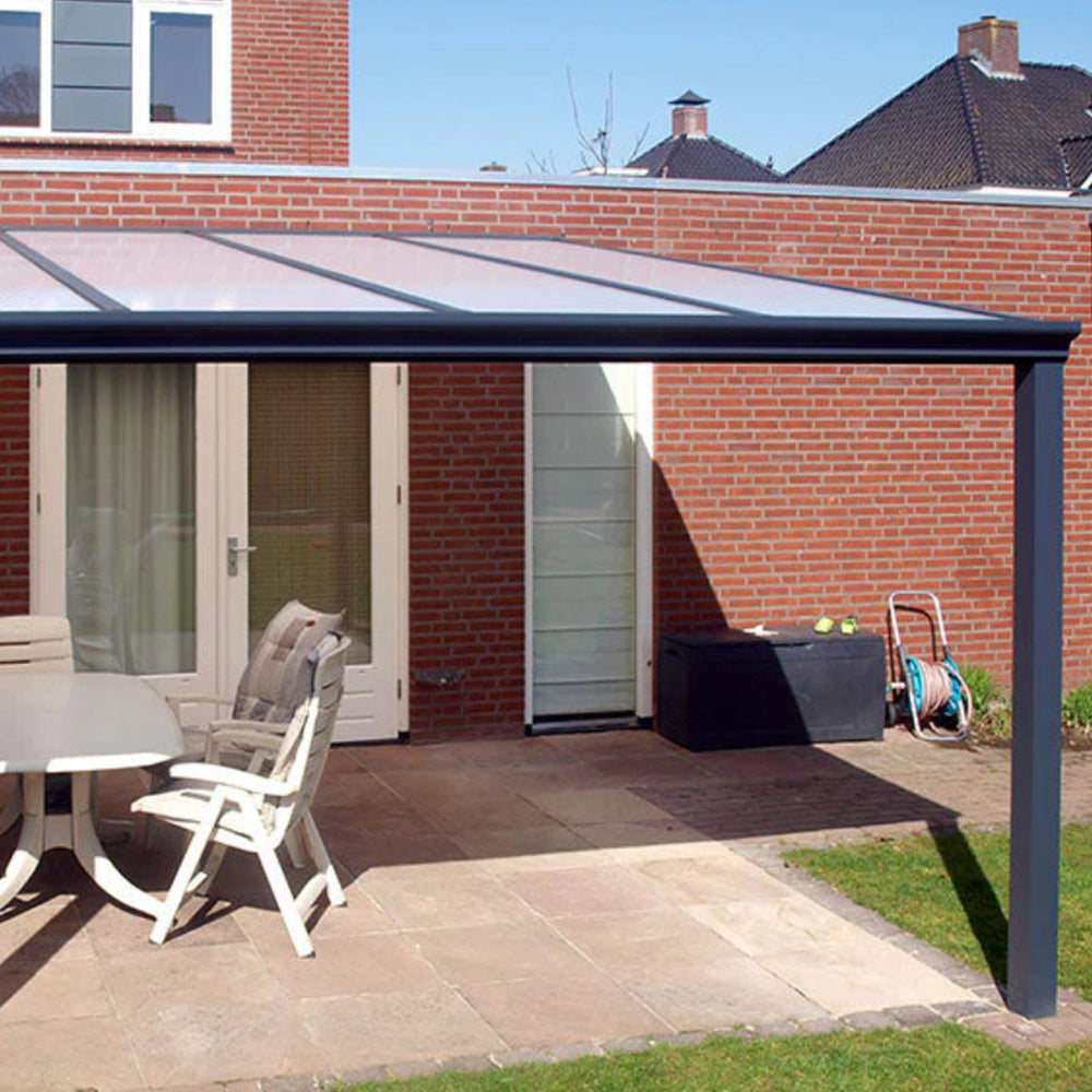 Outdoor patio area with a canopy, table, and chairs in front of a brick house.