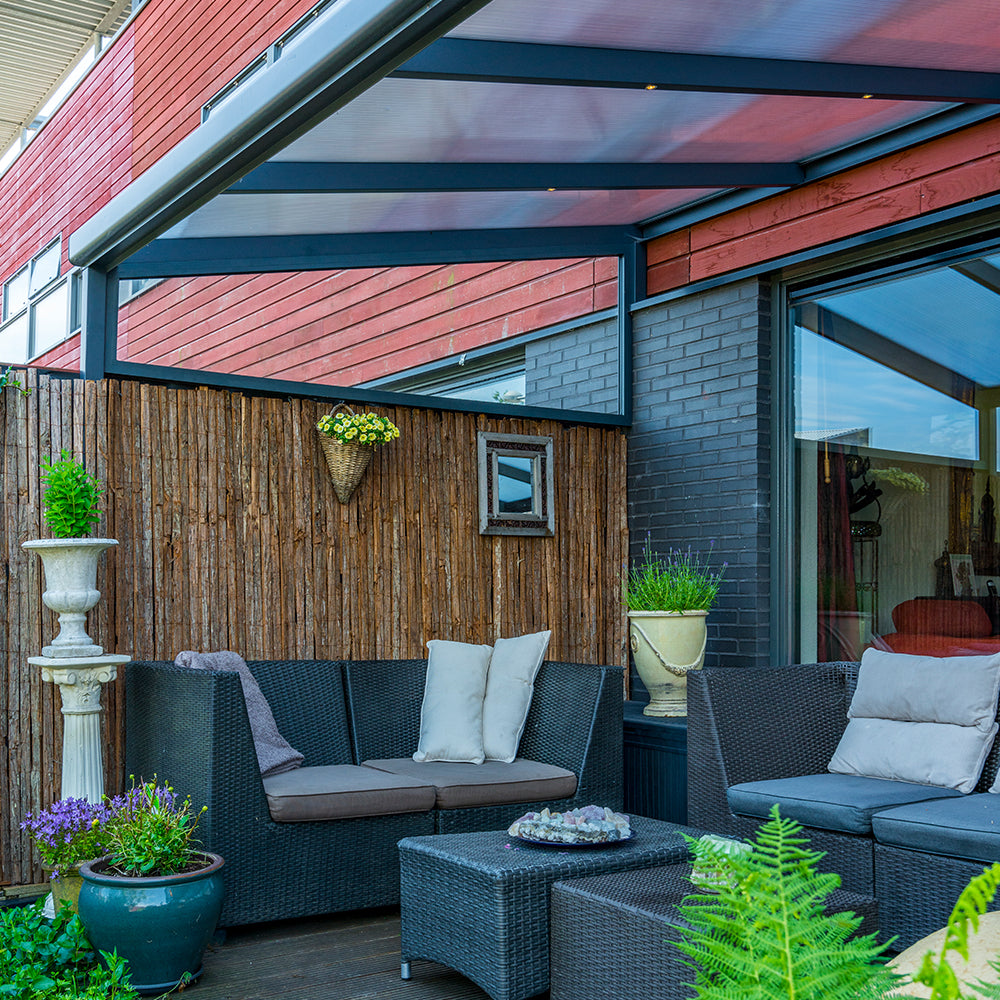 Outdoor patio area with wicker furniture, plants, underneath an aluminium canopy