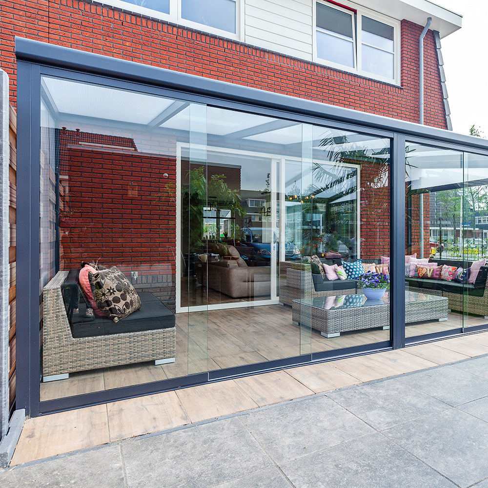 Modern patio canopy with glass walls and outdoor furniture.