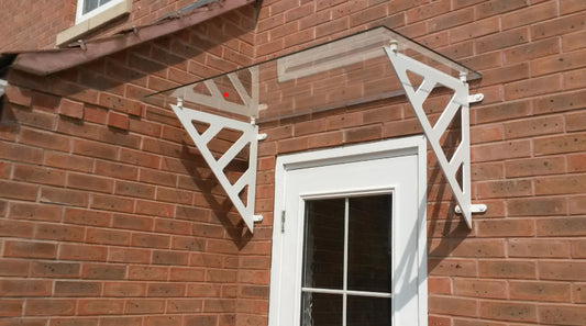 Clear glass over door canopy supported by white brackets on a brick wall.