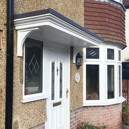 White front door and City 480 door  canopy on a textured beige house exterior with brick detailing.