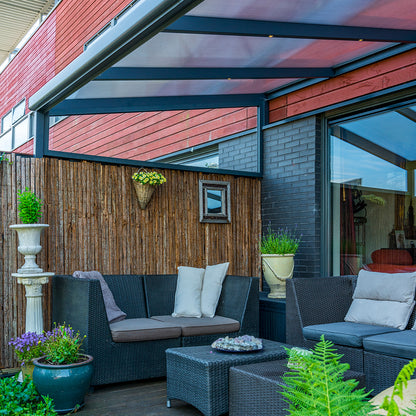 Outdoor patio area with wicker furniture, plants, underneath an aluminium canopy
