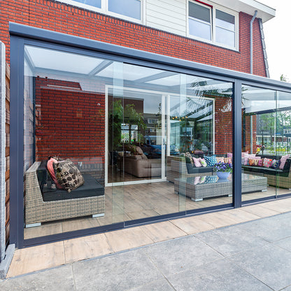 Modern patio canopy with glass walls and outdoor furniture.